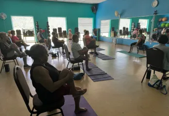 An instructor leads a chair yoga class at the Betty J. Pullum YMCA, beginning with gentle stretches.