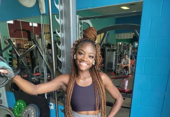 Kenani, a member at the Betty J. Pullum YMCA, poses for a photo near the weights.