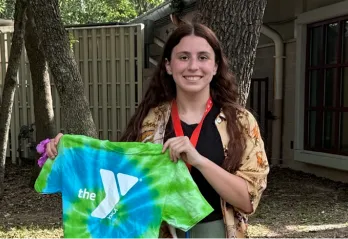 woman standing in a field holding a YMCA T-shirt