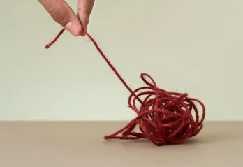 A tangled ball of string is being unwound by pulling on one of the ends.