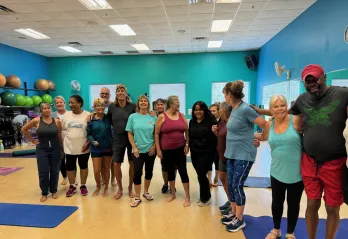 Members in a group exercise class at the Betty J. Pullum Y pose together in a line for a photo.