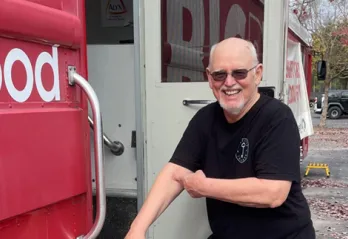 Member stands outside OneBlood bus.