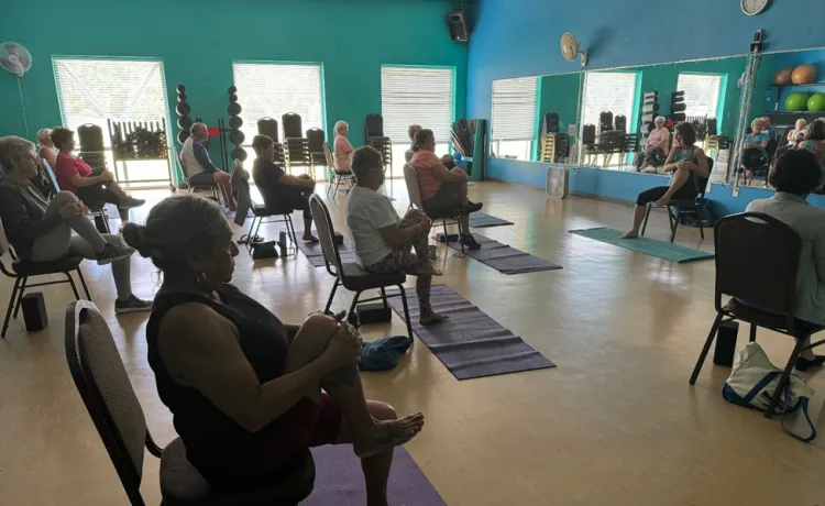 An instructor leads a chair yoga class at the Betty J. Pullum YMCA, beginning with gentle stretches.