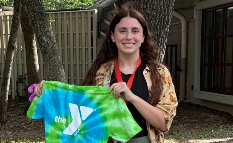 woman standing in a field holding a YMCA T-shirt