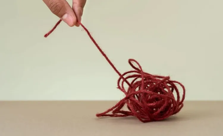 A tangled ball of string is being unwound by pulling on one of the ends.