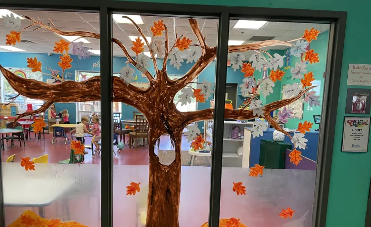 A tree is painted on the windows of KidZone at the Betty J. Pullum Y, with paper leaves decorated by the children.