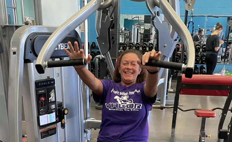 Jackie, a member of the Betty J. Pullum Y, smiles for a photo while she works out at a weight machine.