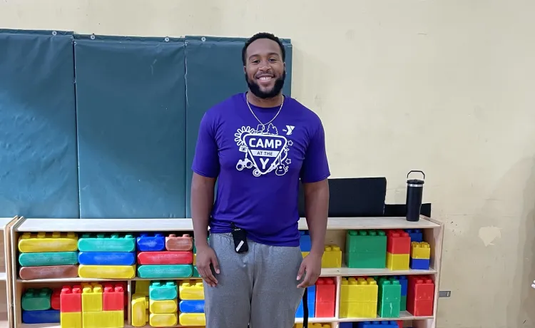 Christian smiles for a photo in the gym as he prepares the area for after school care.