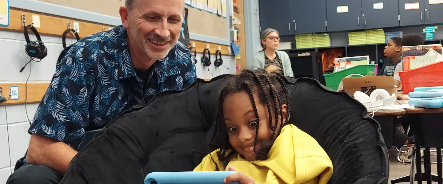 man helps student read on a tablet